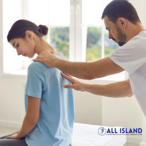Untitled design - 2025-06-11T153555.993 A chiropractor examines a woman's upper back and shoulders in a clinic setting The All Island Chiropractic & Physical Therapy Care logo is visible in the bottom right corner