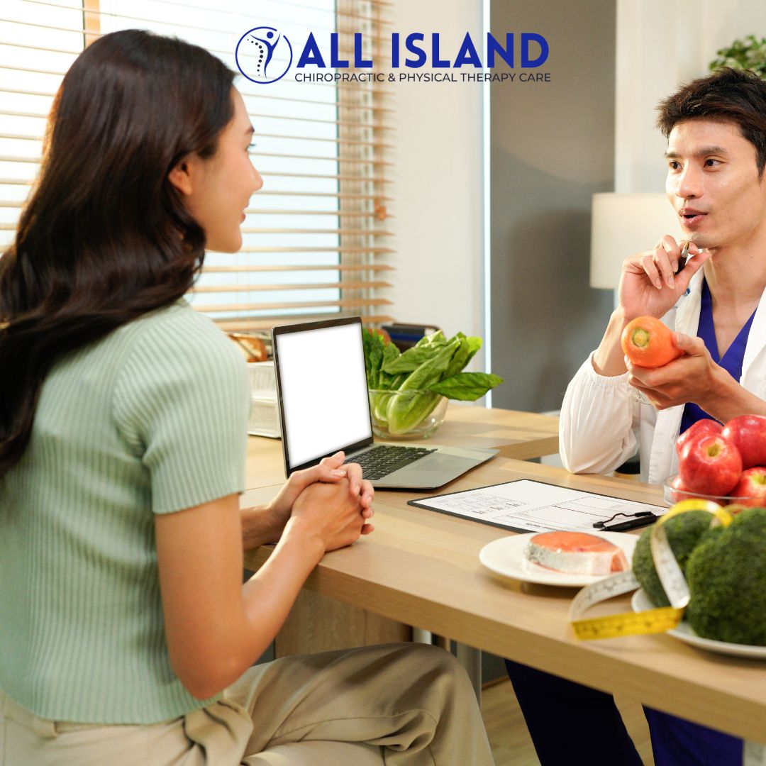 All island Chiro - Chiropractor in Bay Shore NY (6) A nutritionist consults with a woman at a desk with fresh fruits, vegetables, a laptop, and measuring tape; All Island Chiropractic & Physical Therapy Care logo is visible above